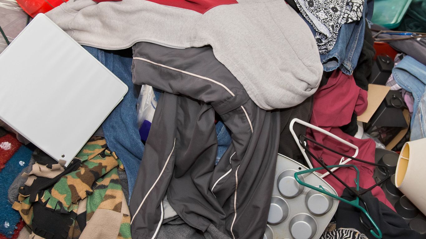 Cluttered room with clothes and items in need of professional house cleanout services in Worcester.