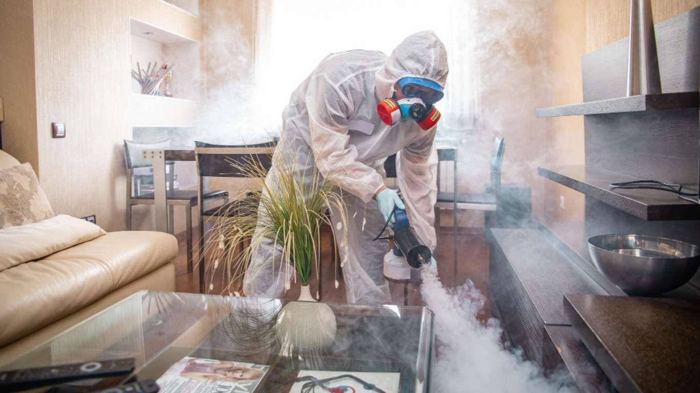 Professional handling odor removal in Dallas, using a fogging machine to clear odors from a living room.